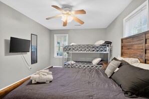 A bedroom with a bunk bed, a ceiling fan, a TV mounted on the wall, and a window with blinds. - Forest Cove Lake Anna | Hot Tub, Games & Boat Slip (Mineral)