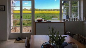 A dining area with a view of a field, a table with a vase of flowers, and a chair. - Holiday home with greenhouse near Mälarhusen (Skåne län)