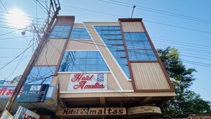 Un hotel con un cartel que dice 'Hotel Amaltas', una fachada moderna con ventanas amplias y un cartel visible de 'G.S. Patel & Co'.