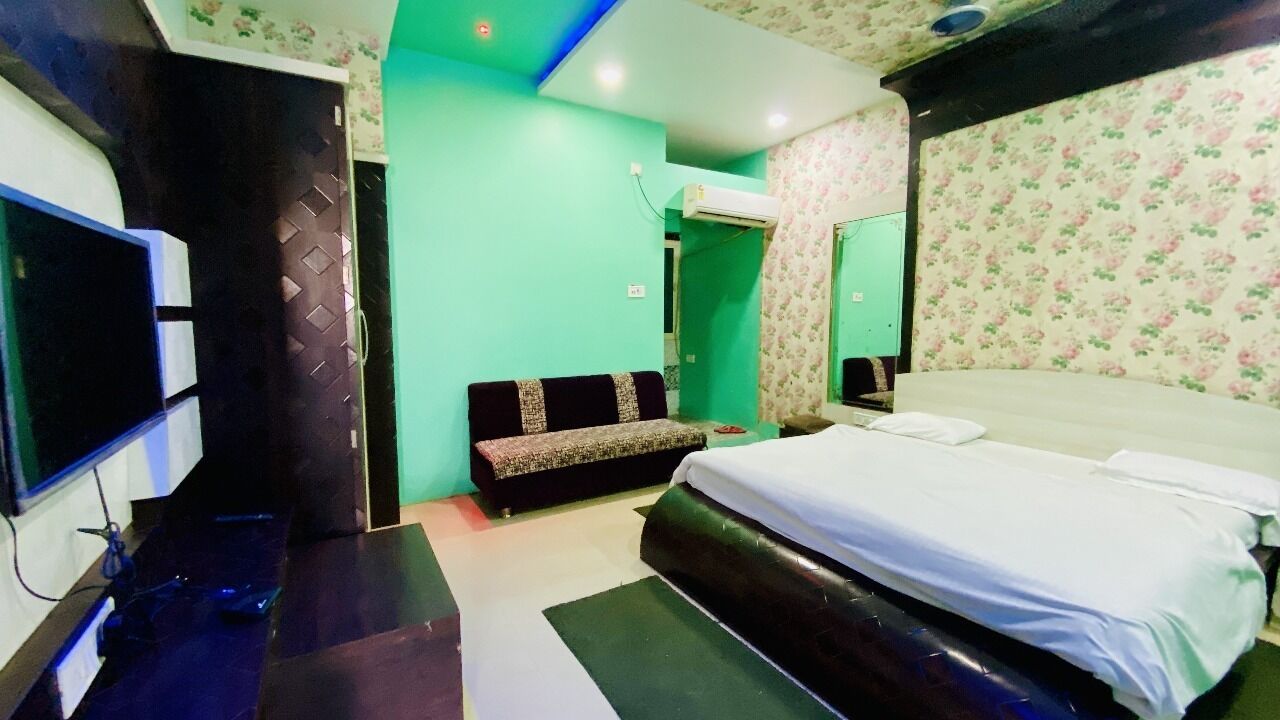 Un dormitorio con cama, televisor, banco y espejo.