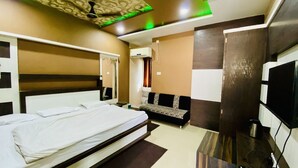 Una habitación de hotel con cama, sofá, televisor y aire acondicionado.