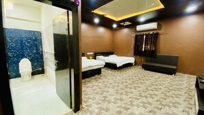 Una habitación de hotel con baño, dos camas, un sofá y una lámpara en el techo.