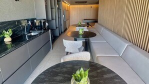 A modern kitchen with a black marble countertop, a round dining table with a potted plant, and a built-in bench along the wall. - Jampa House - Your beachfront apartment in Bessa (João Pessoa)