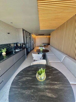 A modern kitchen with a black marble countertop, a round dining table with a potted plant, and a built-in bench along the wall. - Jampa House - Your beachfront apartment in Bessa (João Pessoa)
