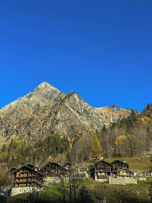 Eine Berghütte mit mehreren Holzhütten, blauem Himmel und einem felsigen Berggrund.