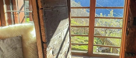 A wooden interior with a sofa, a view through a window, and a wooden floor.
