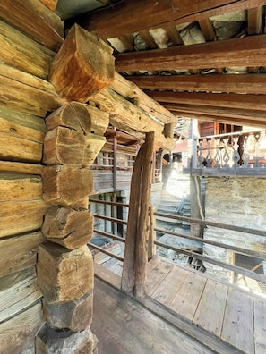 Ein rustikales Holzhaus-Interieur mit Steinwand, Holzbalken und einem Metallgeländer.