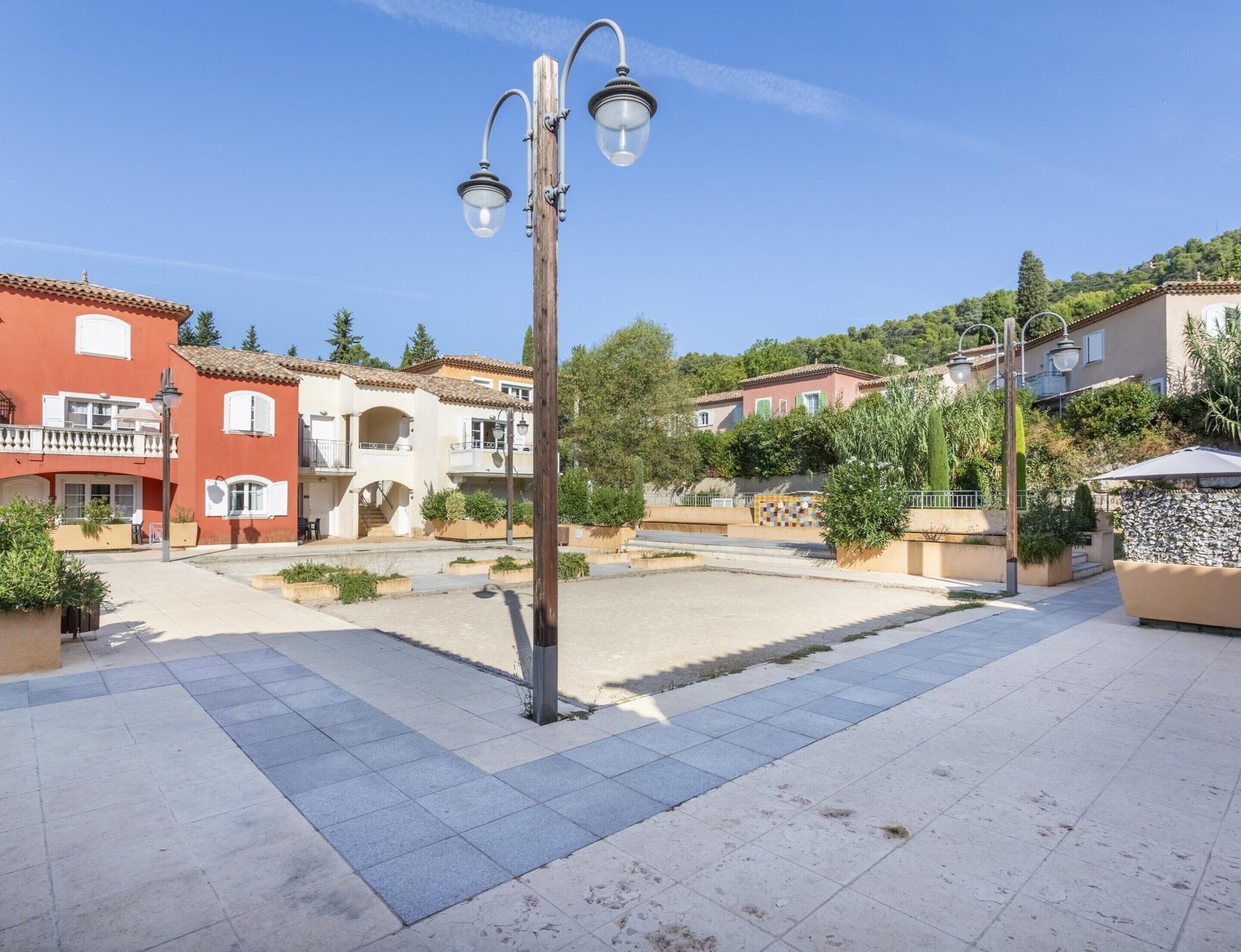 A courtyard with a street lamp, a tiled walkway, and buildings with balconies and windows.