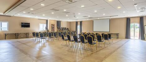 A conference room with a large screen, rows of chairs, and a projector.