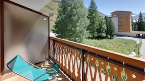 Un balcón con vistas a un edificio, árboles y un paisaje montañoso.