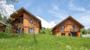 Two wooden cabins with balconies, surrounded by a grassy field. - Attic Apartment With Alpine Charm (Gresse-en-Vercors)