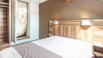 A bedroom with a bed, a wooden headboard, a bedside table, and a mirror.