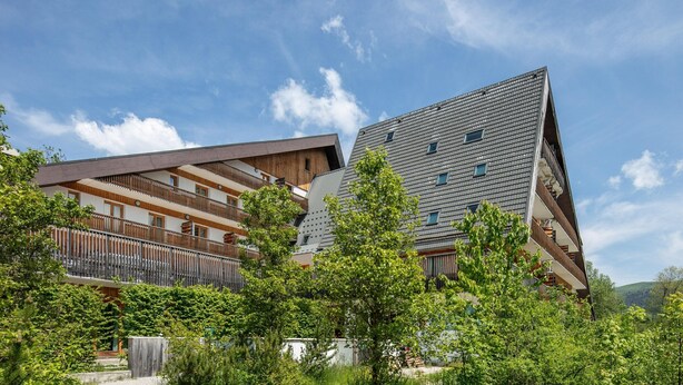 A modern building with multiple balconies, surrounded by lush greenery and a clear blue sky. - Attic Apartment With Alpine Charm (Gresse-en-Vercors)