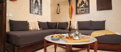 A cozy living room with a sofa, a coffee table with a tray of snacks, and decorative items.