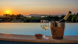 Blick auf einen Pool bei Sonnenuntergang, mit einer Champagnerflasche und Gläsern.