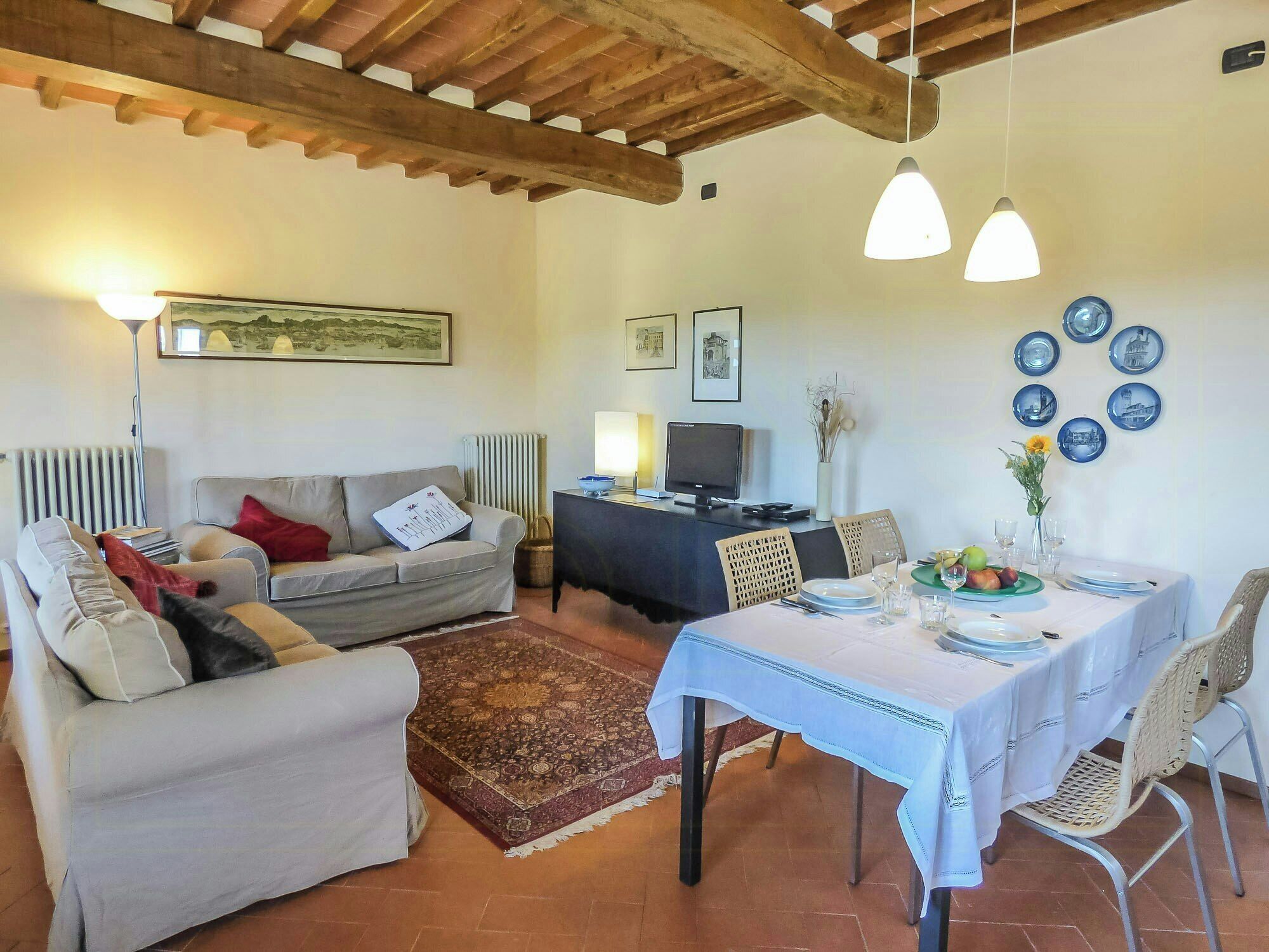 Una sala de estar con un sofá, una mesa de comedor para dos personas y un televisor.