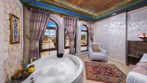 Una habitación con bañera, una silla, una cama y vistas amplias a través de grandes ventanales.
