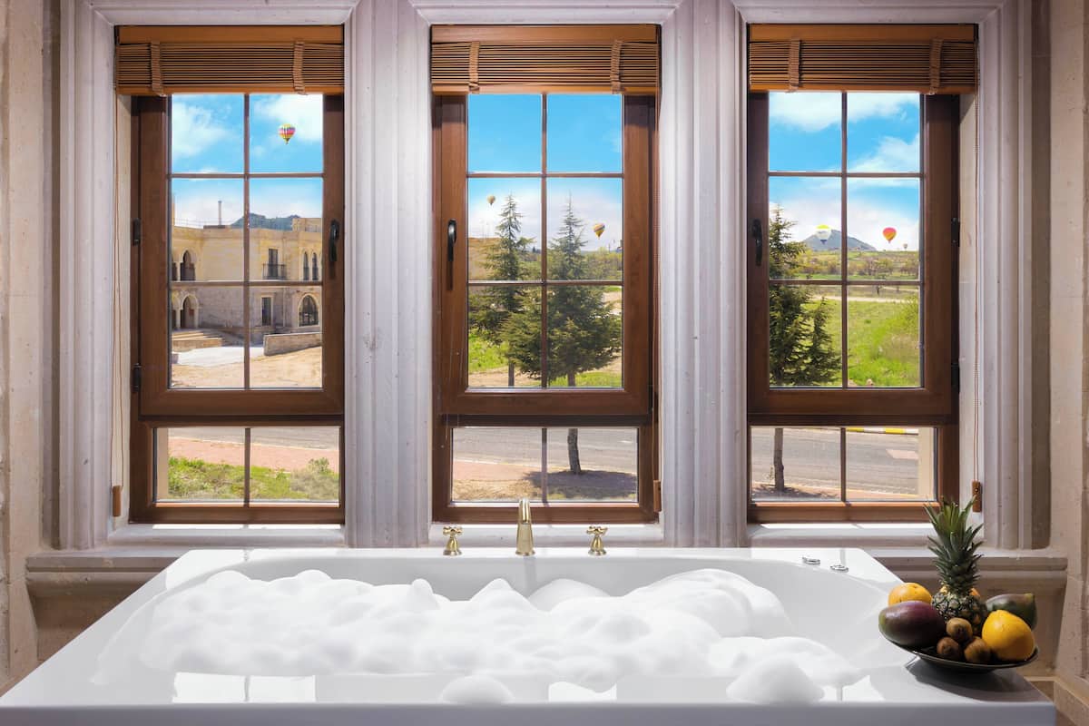 Ein Badezimmer mit einer Badewanne, einem Fenster mit dreifacher Verglasung und einer Obstschale auf der Fensterbank.