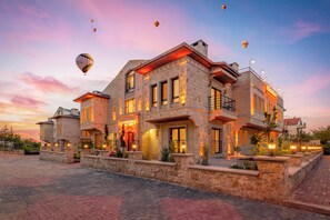 A large stone building with multiple balconies and a well-lit entrance. - Cappadocia Golden Elite (Nevsehir)