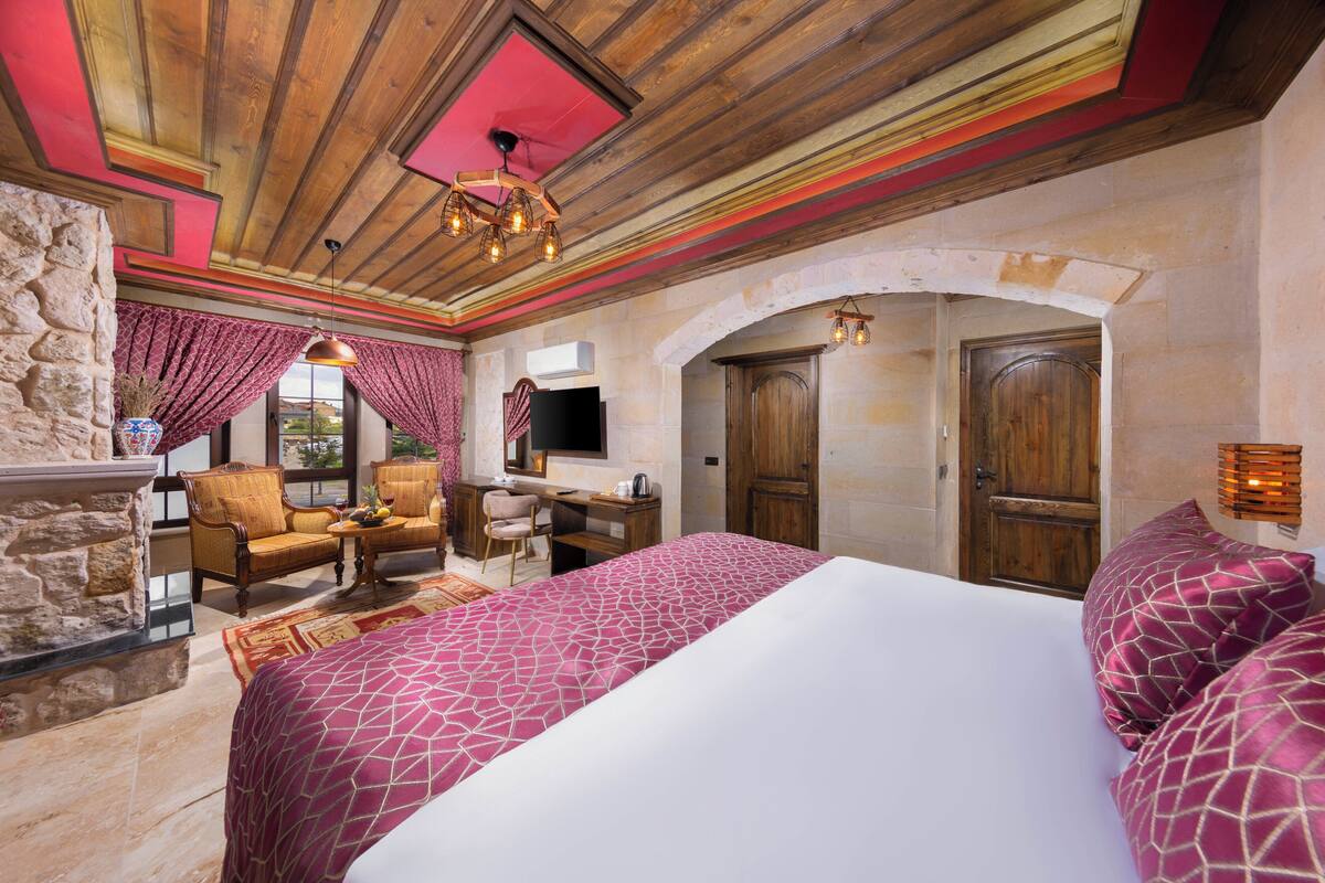 A bedroom with a bed, a desk, a chair, and a stone wall.