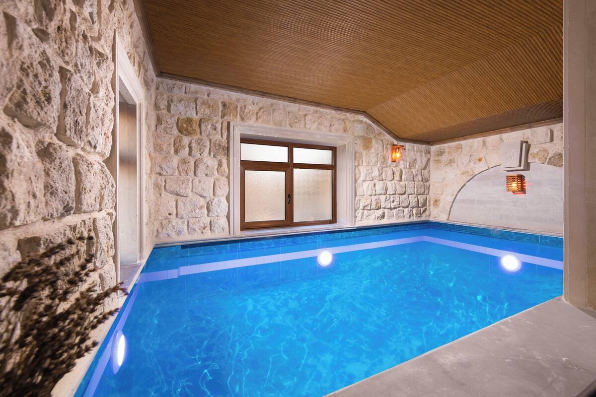 An indoor swimming pool with stone walls and a wooden ceiling.