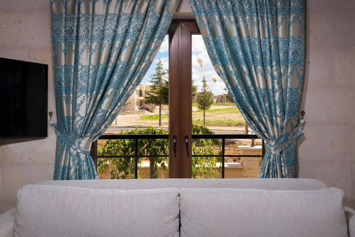 A room with a balcony, a window with blue patterned curtains, and a view of the outside.