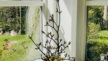 A yellow vase with a branch on a windowsill.