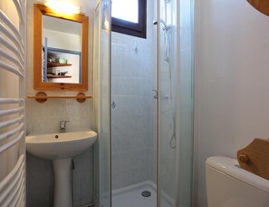Ein Badezimmer mit Waschbecken, Spiegel, Dusche und Toilette.