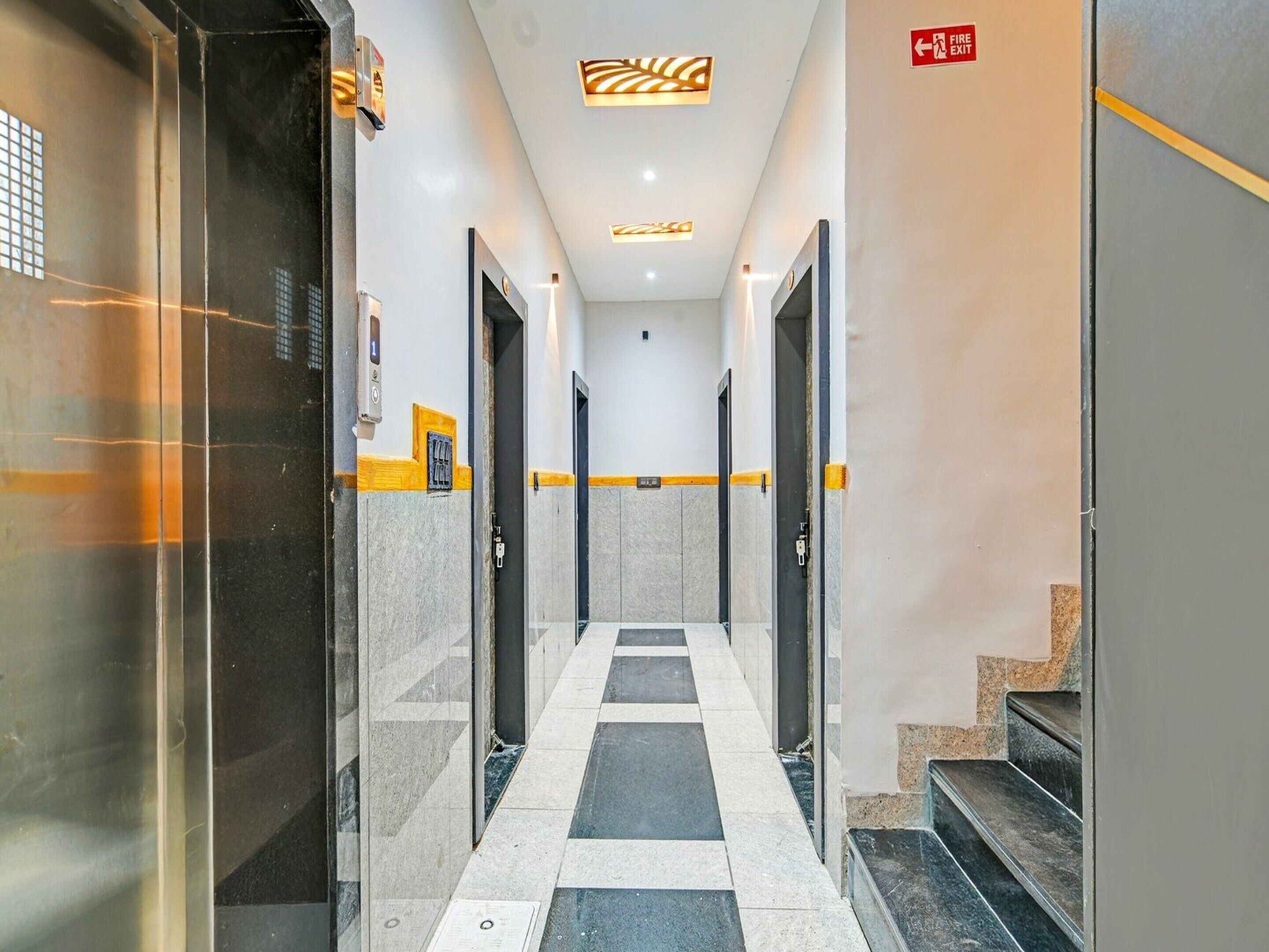 A hallway with a checkered floor, doors on either side, and a fire exit sign.