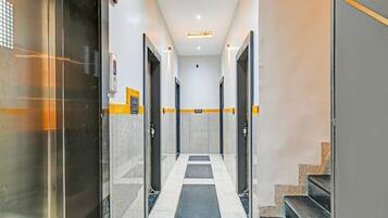 A hallway with a checkered floor, doors on either side, and a fire exit sign.