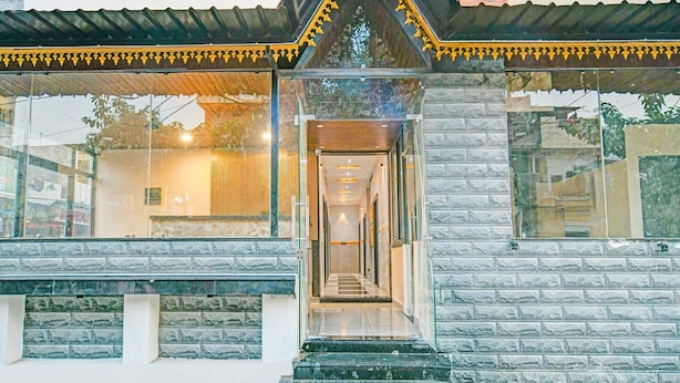 A building with a glass facade, a stone facade, and a triangular roof with decorative trim. - Deluxe Hotel Maharana Pratap (Ujjain)
