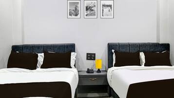 Une chambre d’hôtel avec deux lits, une table de chevet avec une lampe et trois tableaux encadrés au mur.