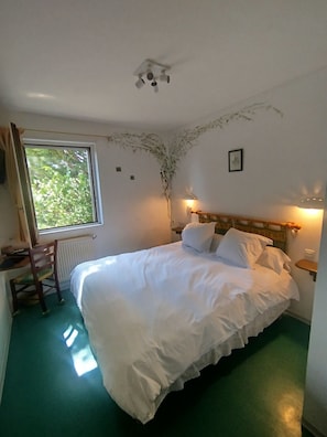 Un dormitorio con cama, una silla, una ventana y un radiador.