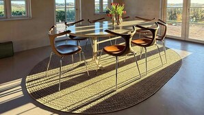 A dining area with a round table, chairs, and a vase of flowers.
