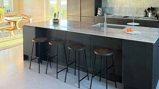 A modern kitchen with a large island, bar stools, and pendant lighting.