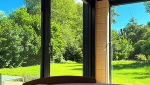 A room with a large window, a wooden ceiling, and a view of a green landscape. - 60s modernism by Rågeleje beach (Vejby)