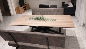 A dining area with a wooden table, cushioned chairs, a sofa, and a TV on a wooden cabinet. - On the wine route and Christmas markets (Beblenheim)