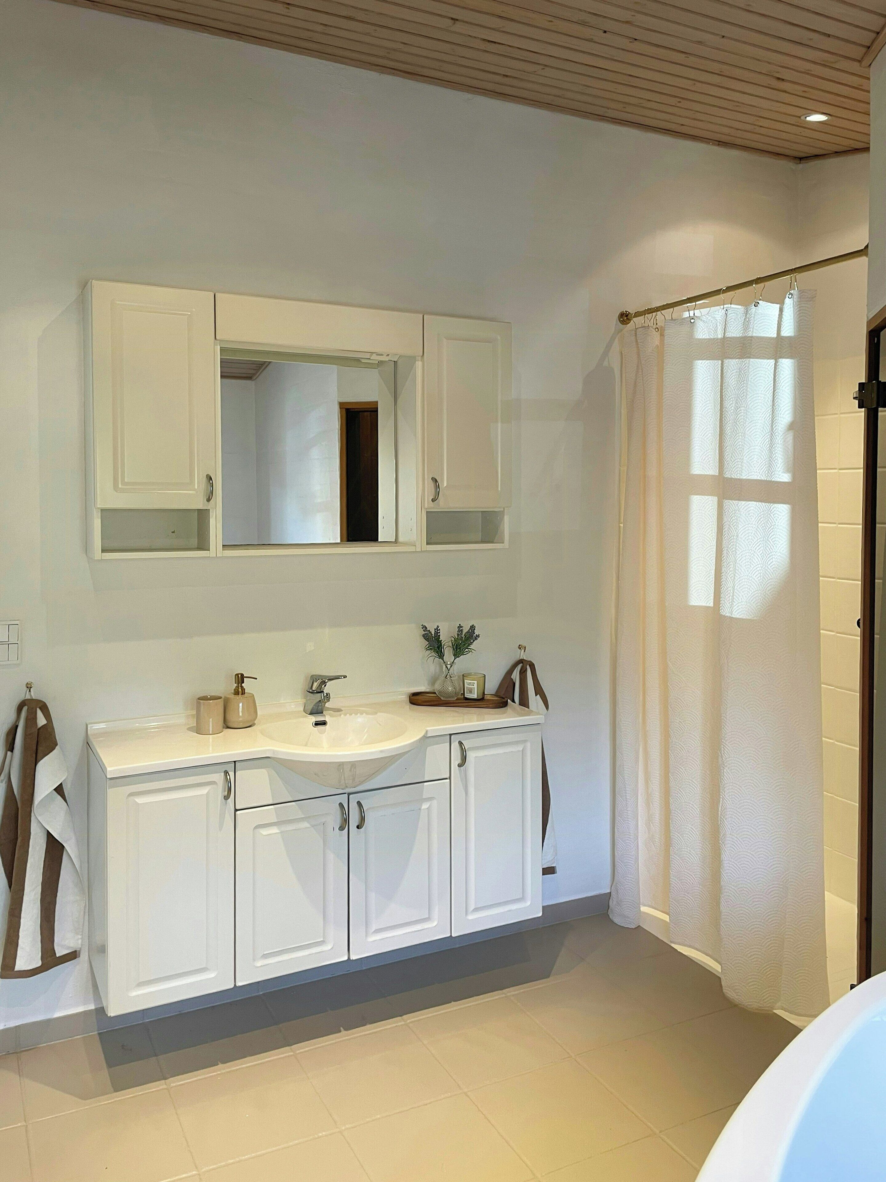 Une salle de bain avec un double lavabo, un miroir, un rideau de douche et un porte-serviettes.