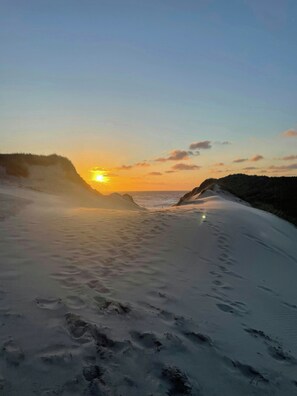 Una playa con un atardecer, arena y huellas.