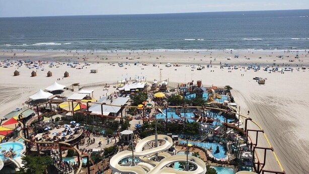 Een strandresort met een waterpark, meerdere zwembaden en strandparasols.