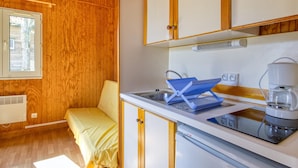Een kleine keuken met houten wanden, een gootsteen, een fornuis en een bed.