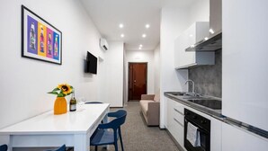 Une cuisine de taille réduite avec des meubles blancs, un four noir et un plan de travail gris.