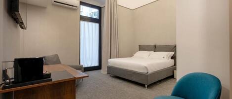 Une chambre d’hôtel équipée d’un lit, d’un bureau, d’une chaise, d’une télévision et d’un appareil de climatisation.