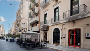 Une rue bordée de terrasses, un café et un immeuble avec une porte rouge et des balcons.