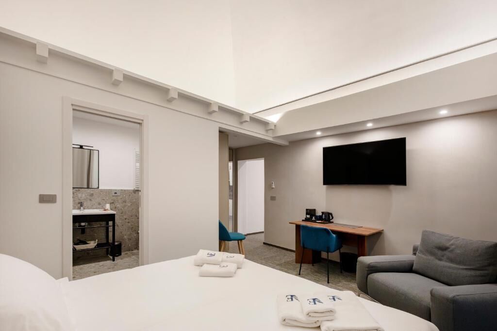 Ein Hotelzimmer mit Bett, Schreibtisch, Fernseher, Sessel und Sofa.