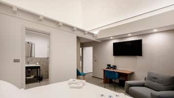 Ein Hotelzimmer mit Bett, Schreibtisch, Fernseher, Sessel und Sofa.