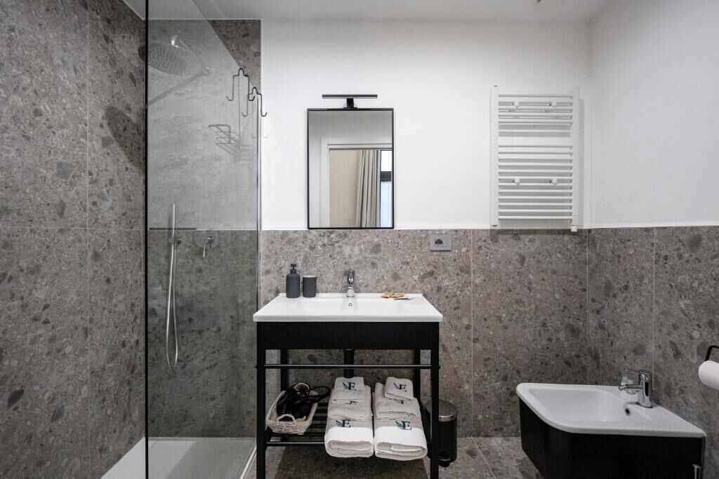 A modern bathroom with a glass shower enclosure, a double sink vanity, and a mirror above the sink.