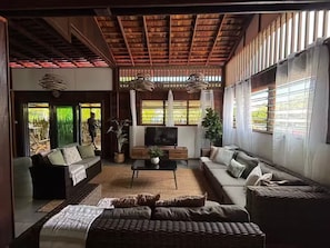A spacious living room with a high ceiling, large windows, a flat-screen TV, and comfortable seating. - KAZ DIBWA Beach House (Machabee)