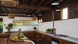 A kitchen with wooden cabinets, a white brick backsplash, and hanging pendant lights.