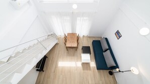 En modern inredning med ett matbord i trä, en soffa, en trappa och ett takfönster.